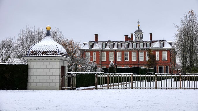 A photograph of the south wing of Hanbury Hall taken from the gardens with the property covered in snow